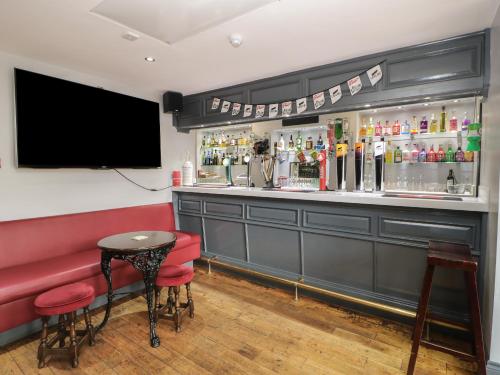 a bar with a red bench and a tv at The Grey Bull Apartment in Hexham