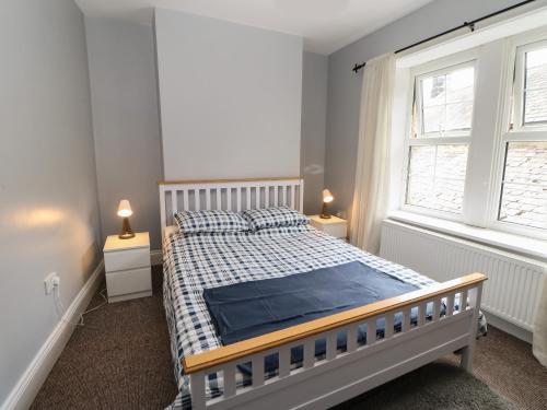 a bedroom with a bed and two windows and two lamps at The Grey Bull Apartment in Hexham