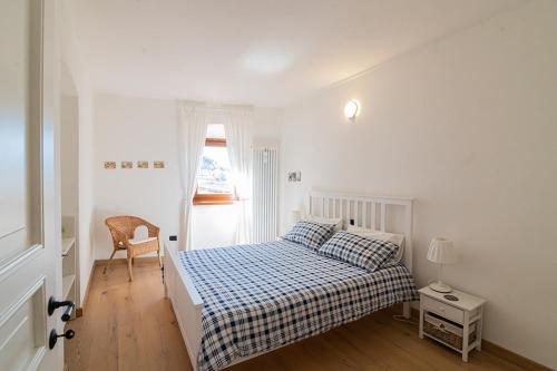 ein weißes Schlafzimmer mit einem Bett und einem Fenster in der Unterkunft cottage lavanda e rosmarino in Lavis