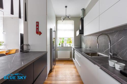 a kitchen with white cabinets and black counter tops at Apartament Blue Sky Jelenia Góra - blisko centrum in Jelenia Góra