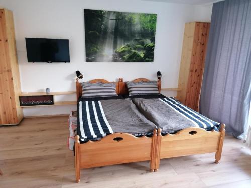 a bedroom with a wooden bed with a tv on the wall at Ferienwohnung Fernblick im Ferienpark Geyersberg in Freyung