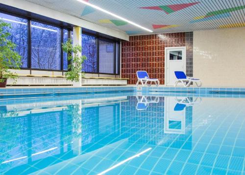 a swimming pool with two chairs in a building at Ferienwohnung Fernblick im Ferienpark Geyersberg in Freyung