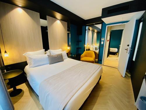 فندق غراند كليشي باريس في كليشي: غرفة نوم مع سرير أبيض كبير في غرفة