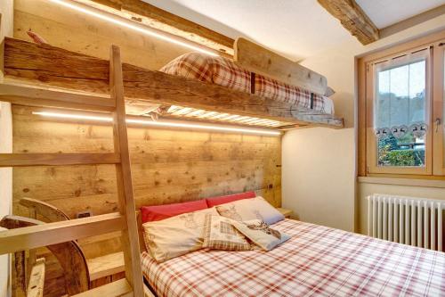 een slaapkamer met een stapelbed en een houten muur bij Casa Clus apartments Bormio 1 in Valdisotto