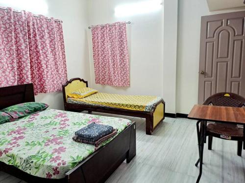 Cette chambre comprend 2 lits, une table et une porte. dans l'établissement Airport 7min/rela 5min/Kitchen/AC/Wifi/Bedroom1, à Chennai