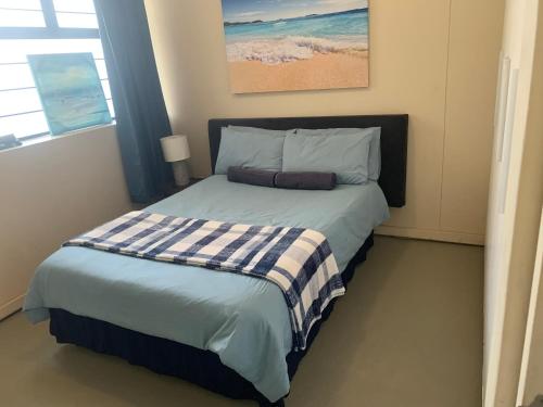 een slaapkamer met een bed met een blauw-witte deken bij The Waves, 302 Quayside Point Waterfront in Durban