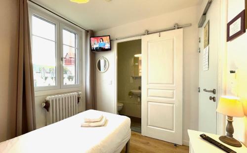 a bedroom with a bed and a bathroom with a window at La Villa Les Mots Passants in Cabourg