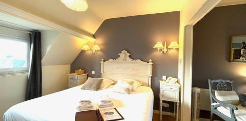 a bedroom with a white bed and a window at La Villa Les Mots Passants in Cabourg