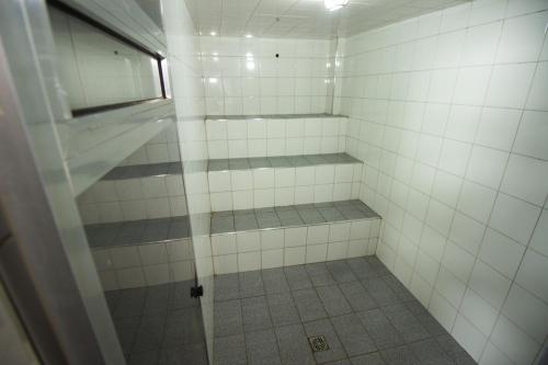 a white tiled shower with a window in a bathroom at Hotel São Charbel in Ubatuba