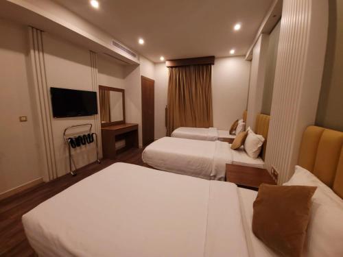 a hotel room with two beds and a flat screen tv at سفير جدة للشقق المخدومة in Jeddah