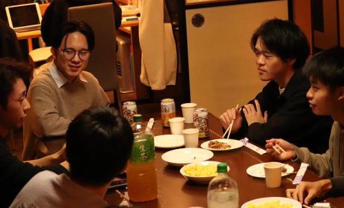 a group of people sitting around a table eating food at 泊まれる図書館 寄処 -yosuga- in Toyama