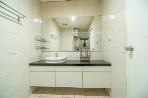 Baño blanco con lavabo y espejo en Bright & Stylish Studio in central Jakarta, SCBD, en Yakarta