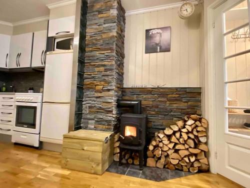 a fireplace in a kitchen with a pile of logs at Sentralt og hjemmekoselig in Narvik