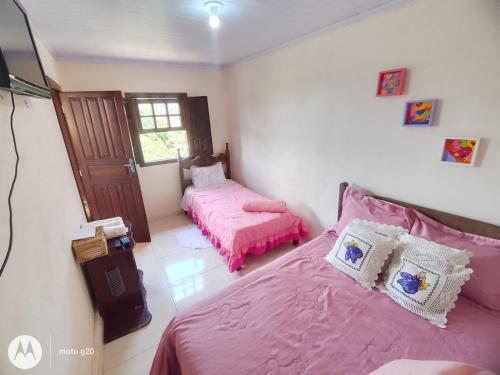 - une chambre avec 2 lits avec des draps roses et une fenêtre dans l'établissement Cantinho da Vovó Lucinda, à Diamantina