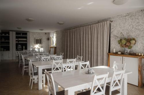 uma sala de jantar com mesas brancas e cadeiras brancas em Willa Natalia em Zielona Góra