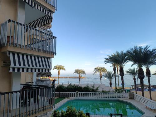 a building with a swimming pool next to the ocean at El Yate Sol y Mar in Aguadulce