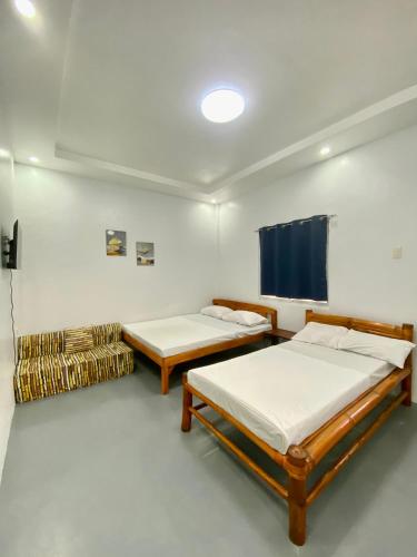 a room with two beds and a tv in it at La Casa Blanca Binoclutan in Botolan