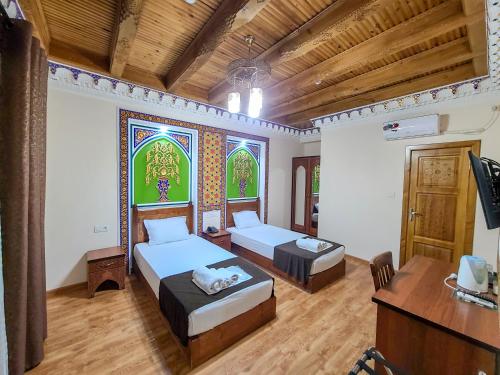 Habitación con 2 camas, escritorio y ordenador. en Old House Hotel, en Bukhara