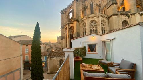 a balcony with chairs and a table in front of a building at L'annexe spa du Tropical Lodge in Narbonne