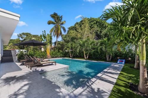 een zwembad met banken en palmbomen in de achtertuin bij Paradise Palms House in Delray Beach