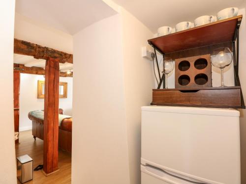 a room with a refrigerator with a shelf on top of it at Leveret Cottage in Docking