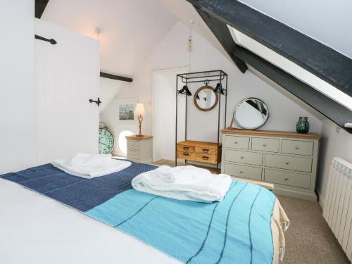 a attic bedroom with a bed and a dresser at Leveret Cottage in Docking