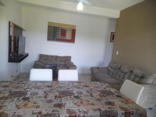 Zimmer mit einem Bett, zwei Stühlen und einem Sofa in der Unterkunft Peruíbe - Oasis - Casa espaçosa, lugar tranquilo in Peruíbe