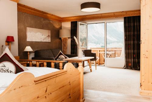 a bedroom with a bed and a couch and a table at Hotel Hohenfels in Tannheim