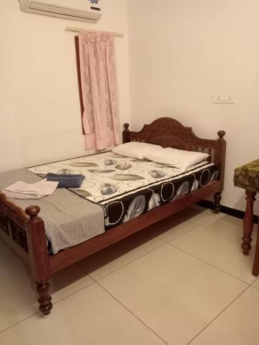 a wooden bed in a room with a window at Yasin Guest house in Puducherry