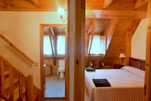 a bedroom in a log cabin with a bed and a bathroom at La Casita de la Sierra Cercedilla in Cercedilla