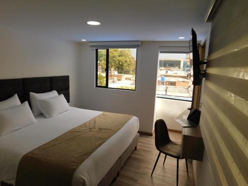 1 dormitorio con cama, escritorio y ventana en HOTEL MX BOGOTA, en Bogotá