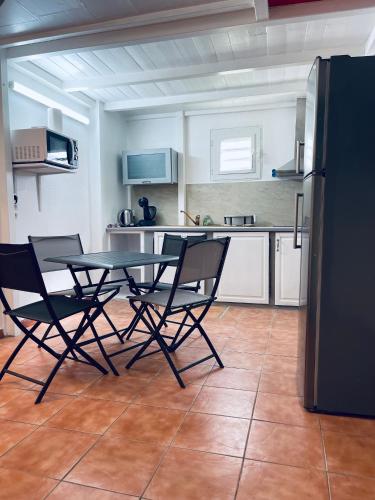 a kitchen with a table and chairs and a refrigerator at Plage St-Anne T2 duplex sans vue in Sainte-Anne