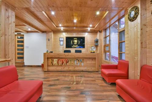 a lobby with two red chairs and a television at The Bliss Cottage Manali Luxury Apartment and villa in Manāli