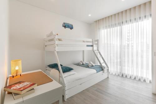 a white bedroom with a bunk bed and a desk at Consolação Wave Beach House in Atouguia da Baleia