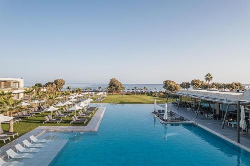 un complexe avec une piscine avec des chaises longues et l'océan dans l'établissement Myrion Beach Resort & Spa - Adults Only, à Gerani