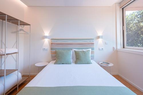 a bedroom with a large white bed and a window at Quinta Das Essências in Penafiel