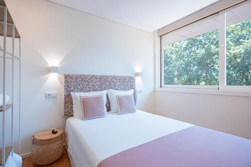 a bedroom with a white bed with a window at Quinta Das Essências in Penafiel