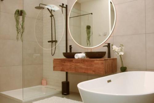 uma casa de banho com uma banheira, um lavatório e um espelho. em The Comfort of a Luxury Hotel, but with your own fully equipped Kitchen em Loosdrecht