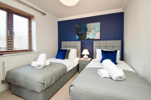 2 camas en un dormitorio con azul y blanco en Spacious 4 Bedroom 3 Bathroom House - Sleeps up to 8 - Free Parking, Balcony, Fast Wifi and Smart TVs by Yoko Property en Milton Keynes