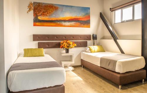 a bedroom with two beds and a painting on the wall at Hotel Wess in Bogotá