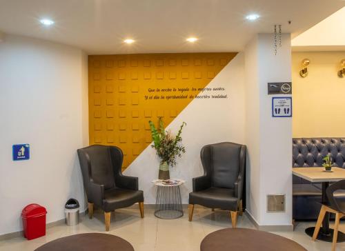a waiting room with two chairs and a yellow wall at Hotel Wess in Bogotá
