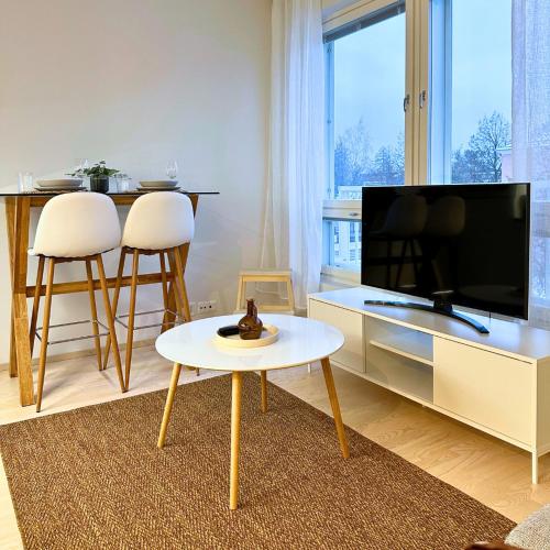 a living room with a table and a tv at Pramea Apartments Pikku Pietari in Kuopio