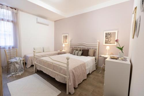 a white bedroom with two beds and a window at My Sicily Home - Casa con giardino in Salemi