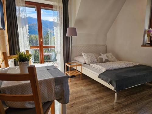 a bedroom with a bed and a table and a window at Panorama Szymaszkowa in Zakopane