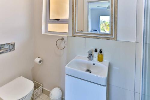 a bathroom with a sink and a toilet and a mirror at Les Dauphine 3 - Premier Beach Front Apartment in Ballito