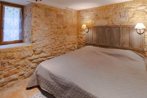 um quarto com uma cama e uma parede de pedra em Gite Beynac em Sainte-Mondane