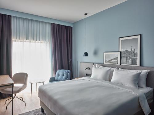 - une chambre avec un lit, un bureau et une chaise dans l'établissement Radisson Hotel Budapest BudaPart, à Budapest