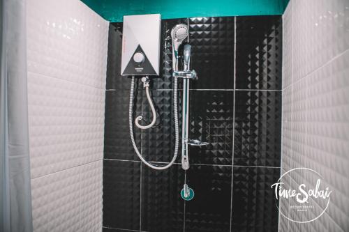 a shower in a black tiled bathroom at Time Sabai 134 in Bangkok