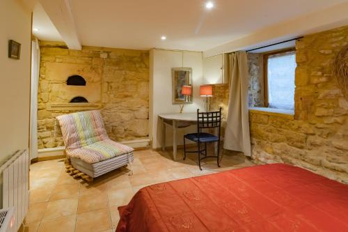 sypialnia z kamienną ścianą, krzesłem i biurkiem w obiekcie Gite Monfort w mieście Sainte-Mondane