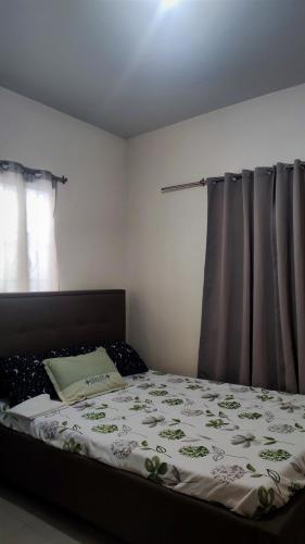 a bedroom with a bed with a comforter on it at MESSÉ Home Stay in General Santos